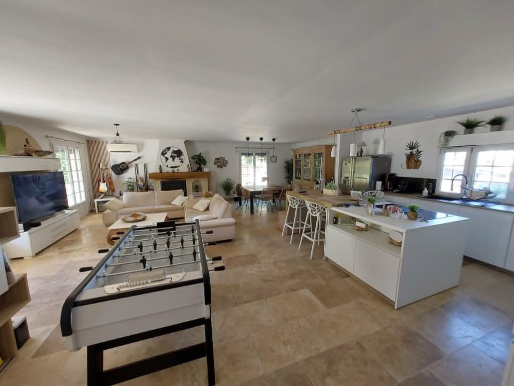 intérieur d'une villa maison contemporaine moderne de la bastide masteli avec baby-foot, cuisine moderne toute équipée, grand salon séjour, pièce de vie avec travertin au sol, meubles contemporains